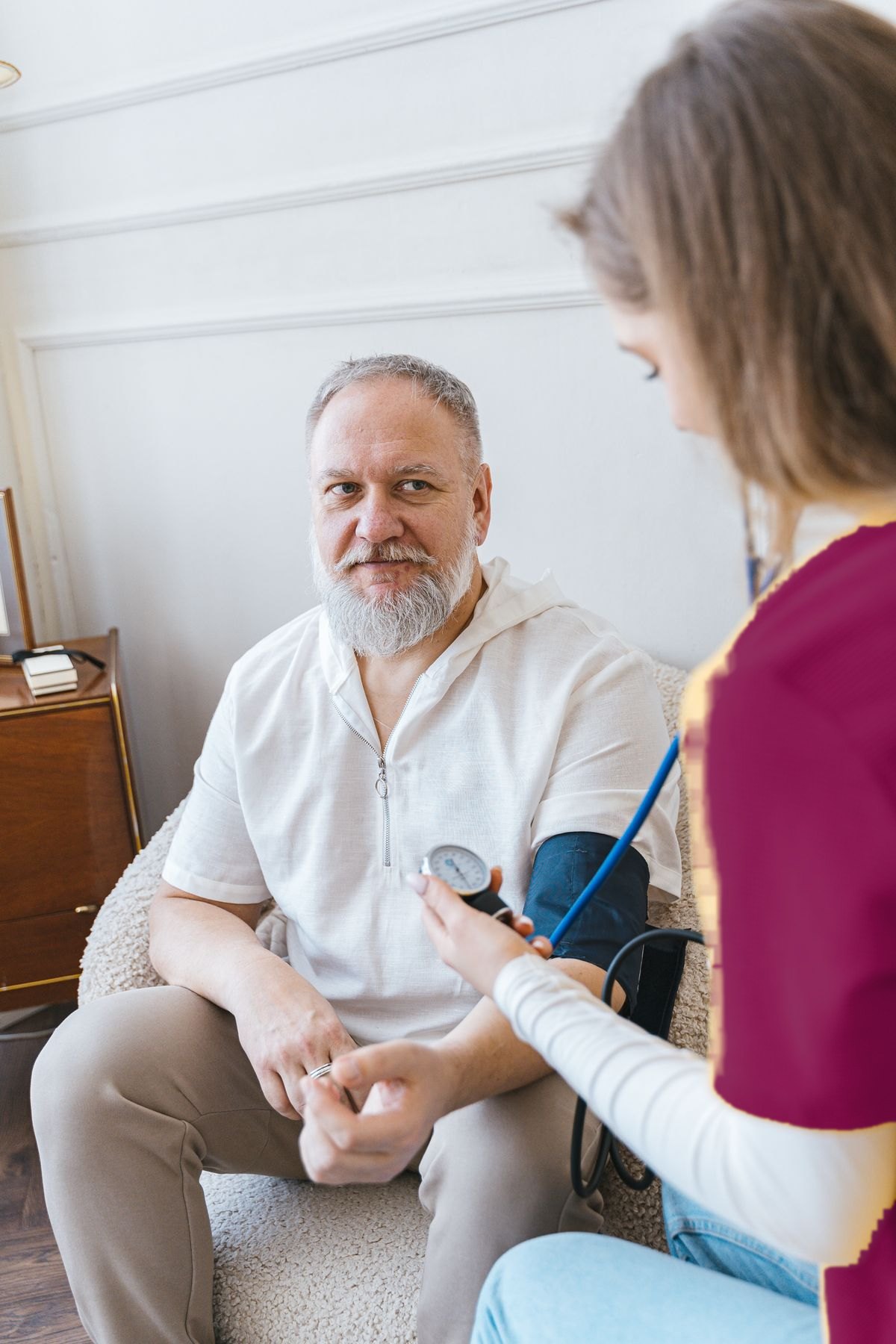 Pflegekraft misst bei einem Senior zu Hause den Blutdruck